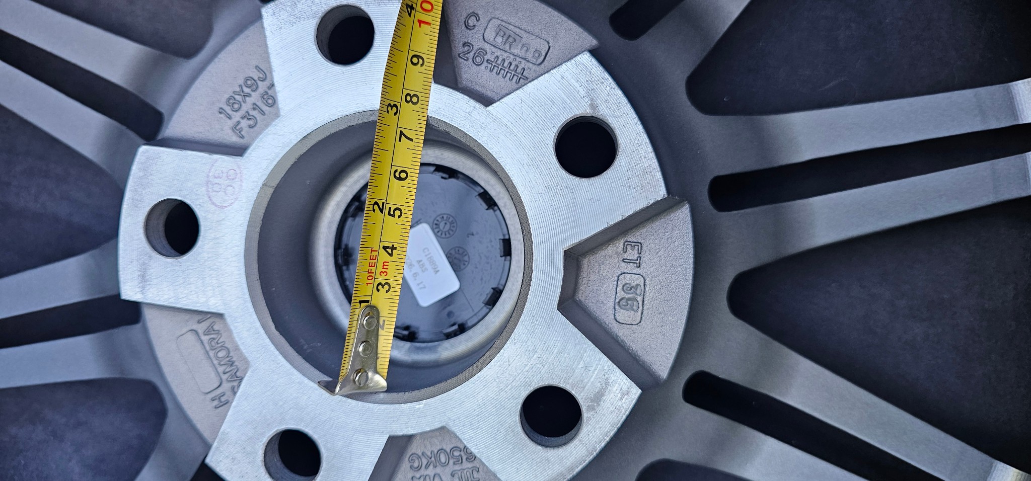 Midiendo con un metro el agujero central de una llanta Samorai, de 72,6 mm, con las marcas 18X9J y JWL VIA grabadas alrededor